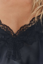 Black lace top worn by a person with blonde hair, close-up view.